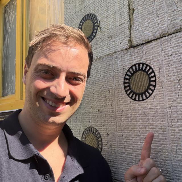 A member of Drastic's German Demonstrator next to circular insulation façade.